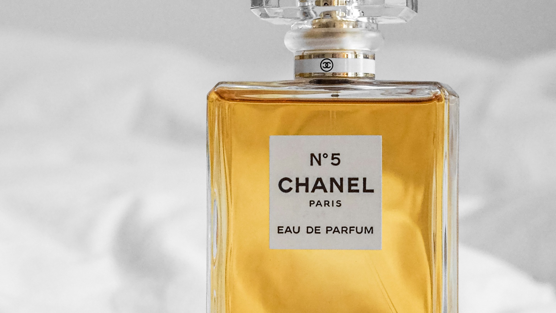 a bottle of perfume sitting on top of a bed