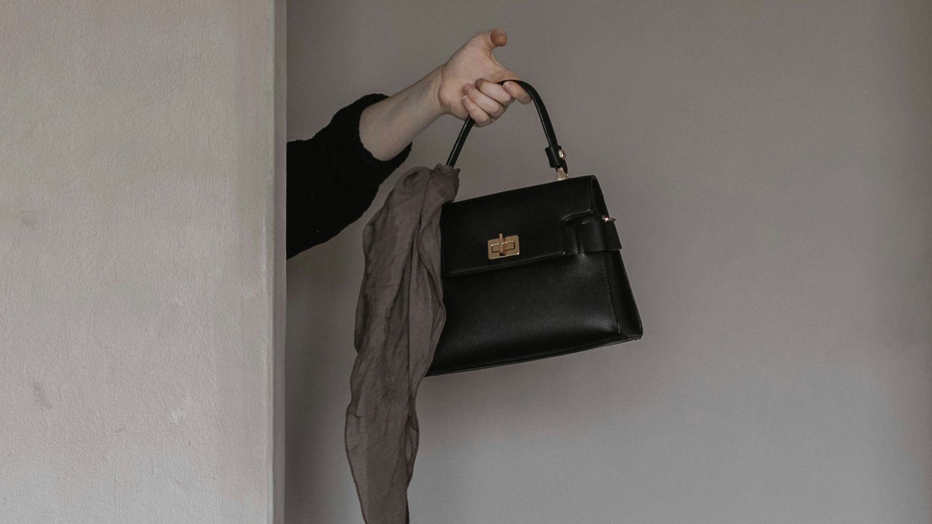 person holding black leather handbag