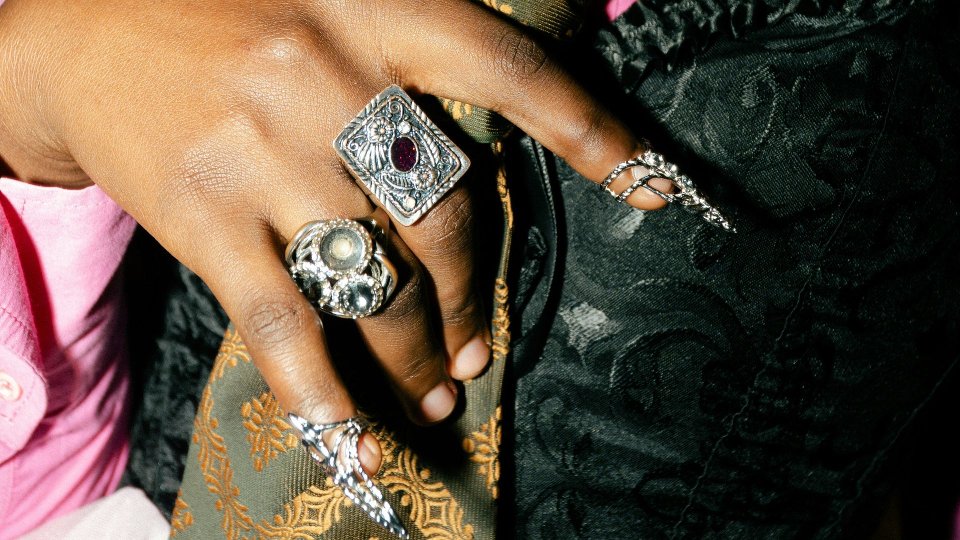 Person wearing a pink shirt, corset, and patterned tie.