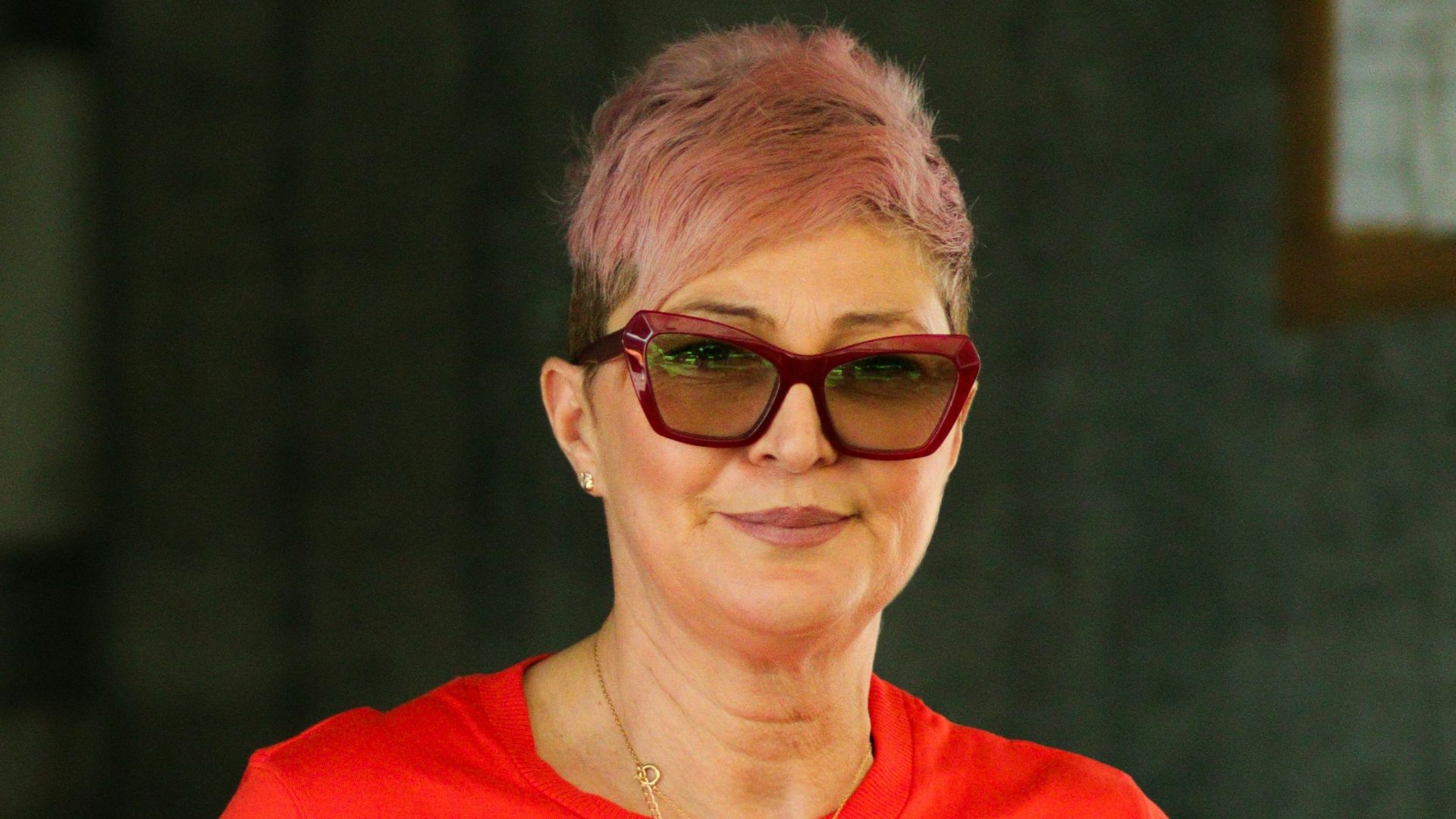 a woman in a red shirt is holding a green origami