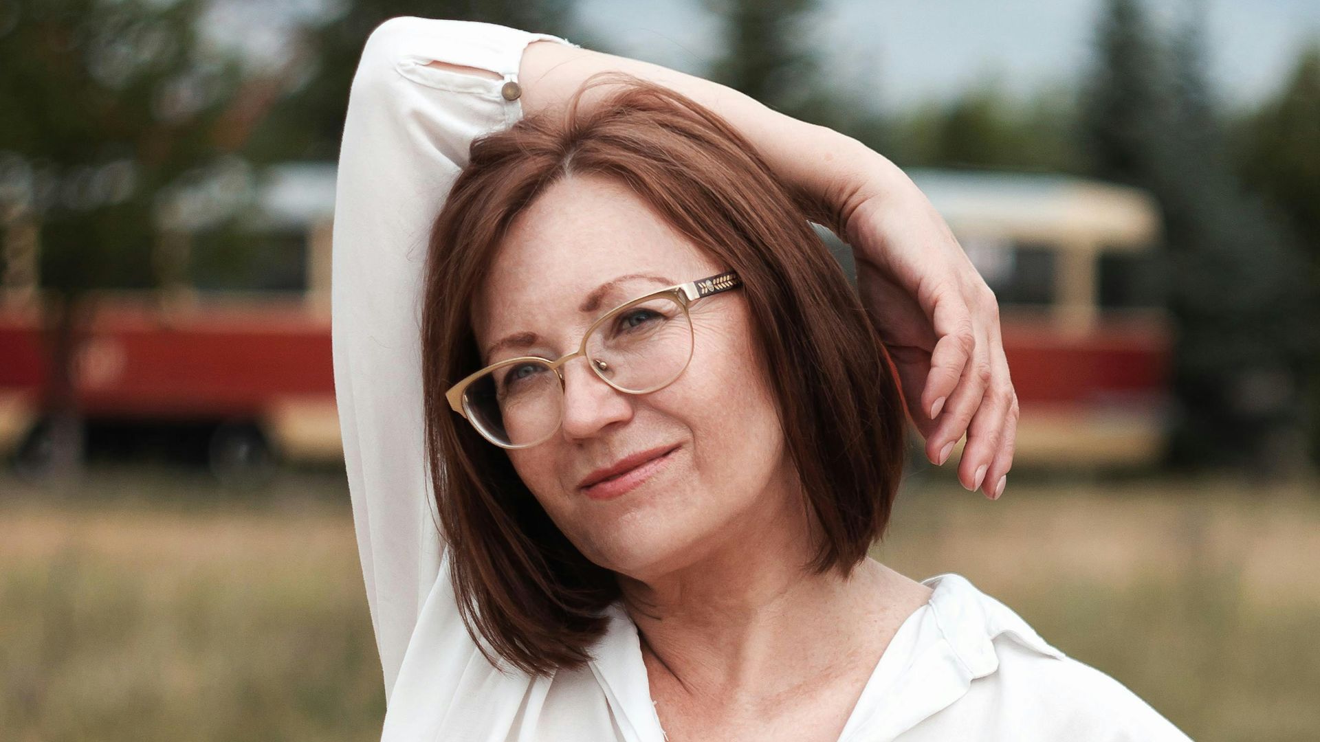 woman in white button up shirt and blue skirt standing on brown sand during daytime