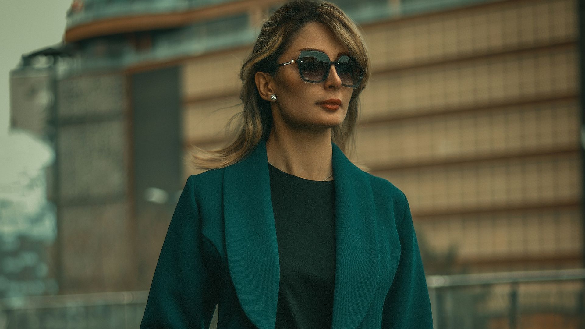 a woman walking down a street carrying a black purse