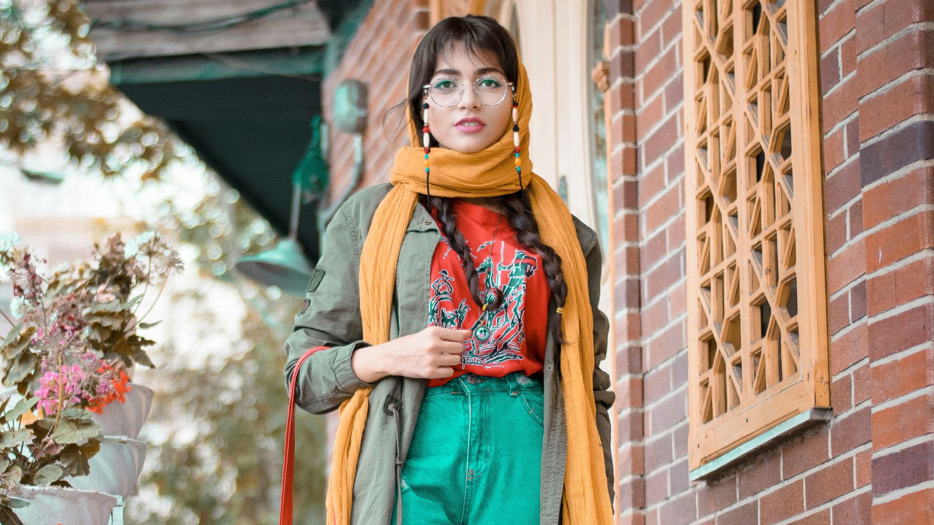 woman in green and brown sari standing beside brown brick wall