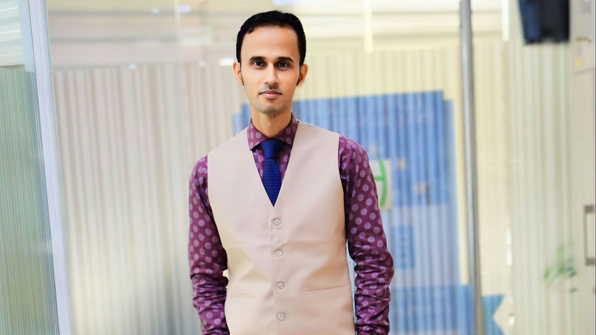 A man in a vest and tie standing in a hallway