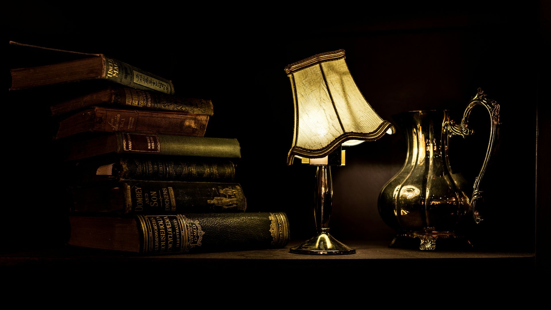 turned on desk lamp beside pile of books