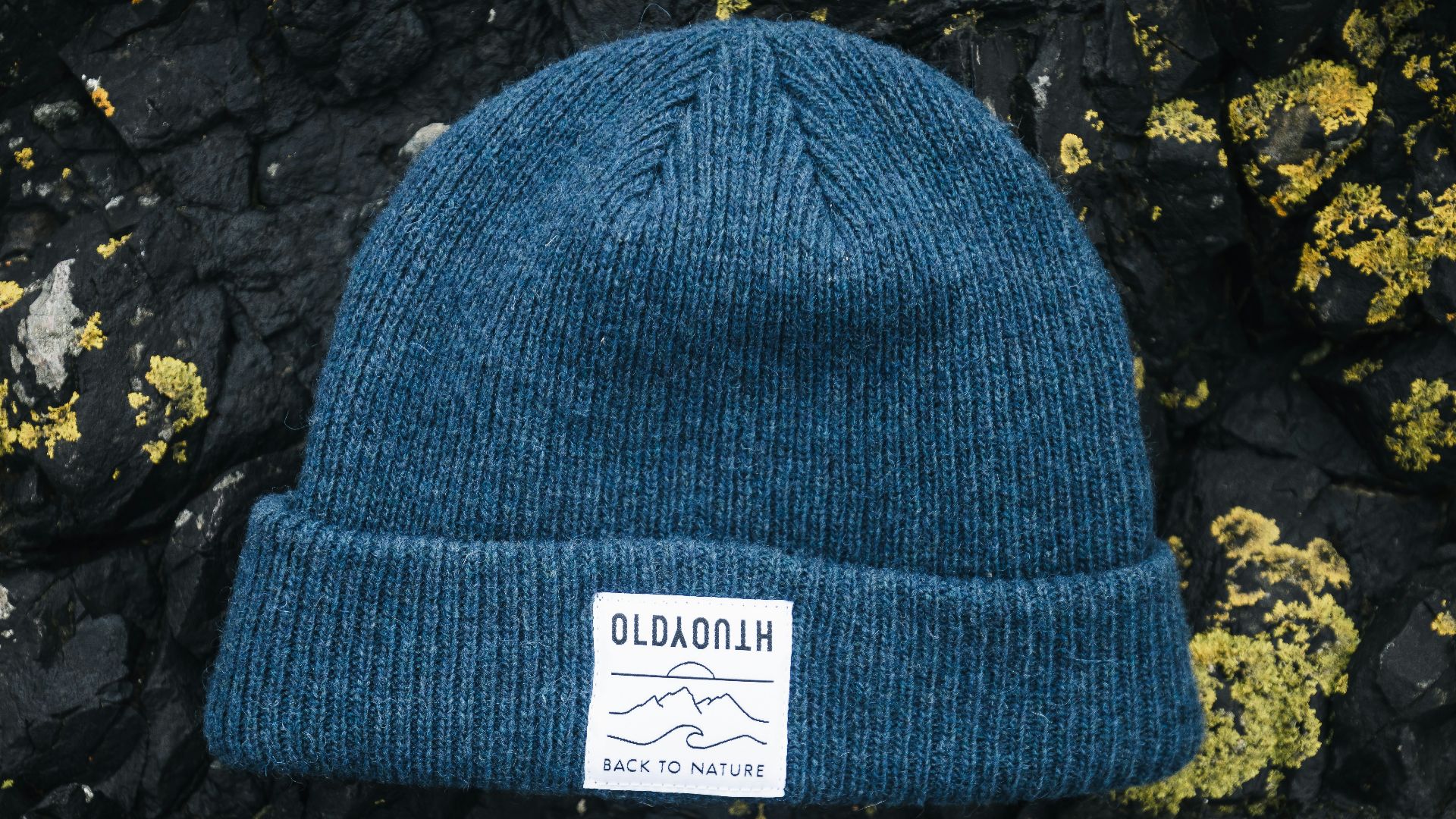 a blue hat sitting on top of a rock covered in lichen