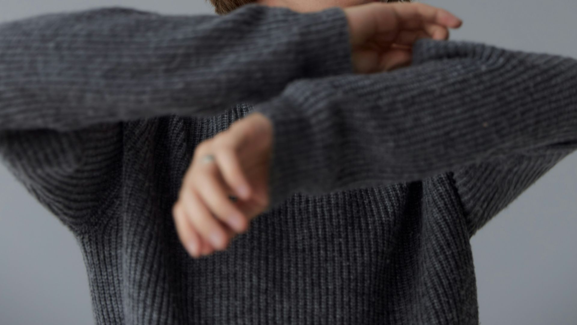 girl in gray sweater covering her face with her hand