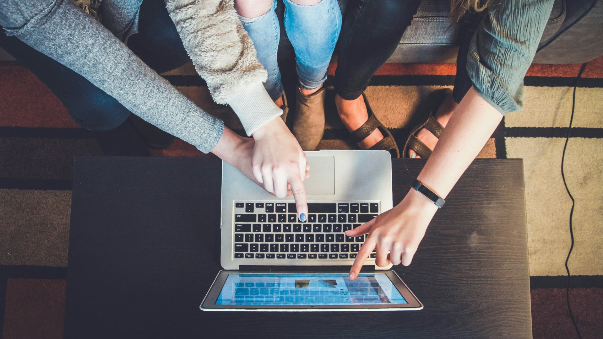 three person pointing the silver laptop computer
