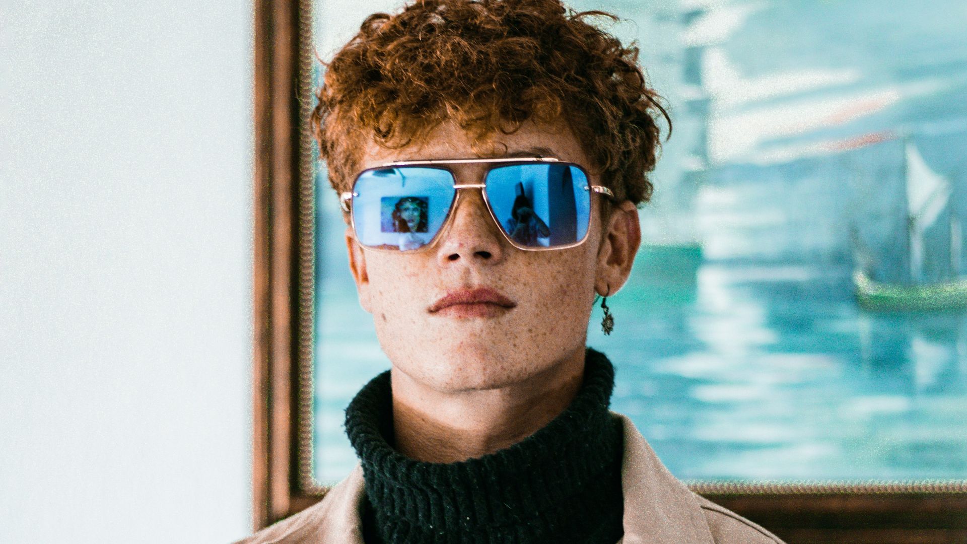 a young man with red hair wearing blue glasses