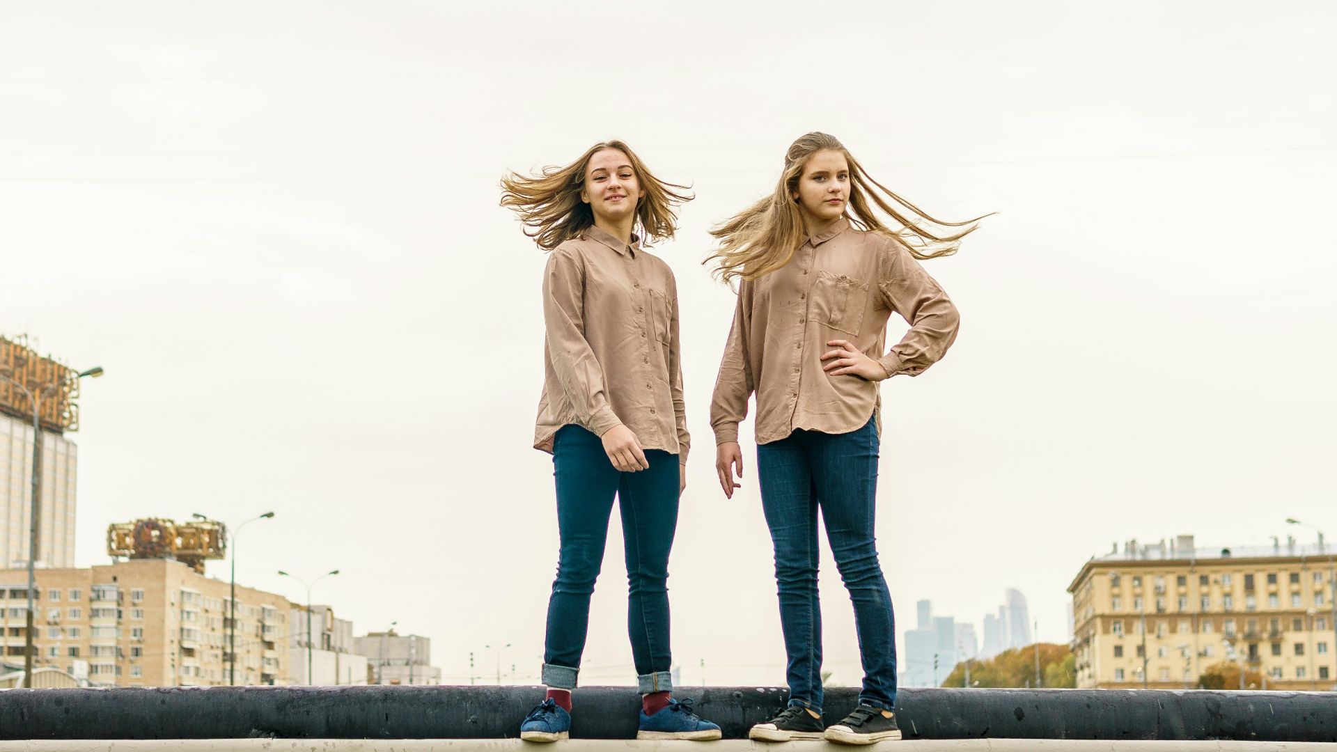 two women standing on a ledge in front of a city