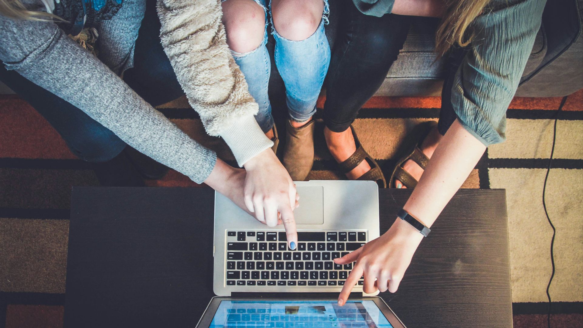 three person pointing the silver laptop computer