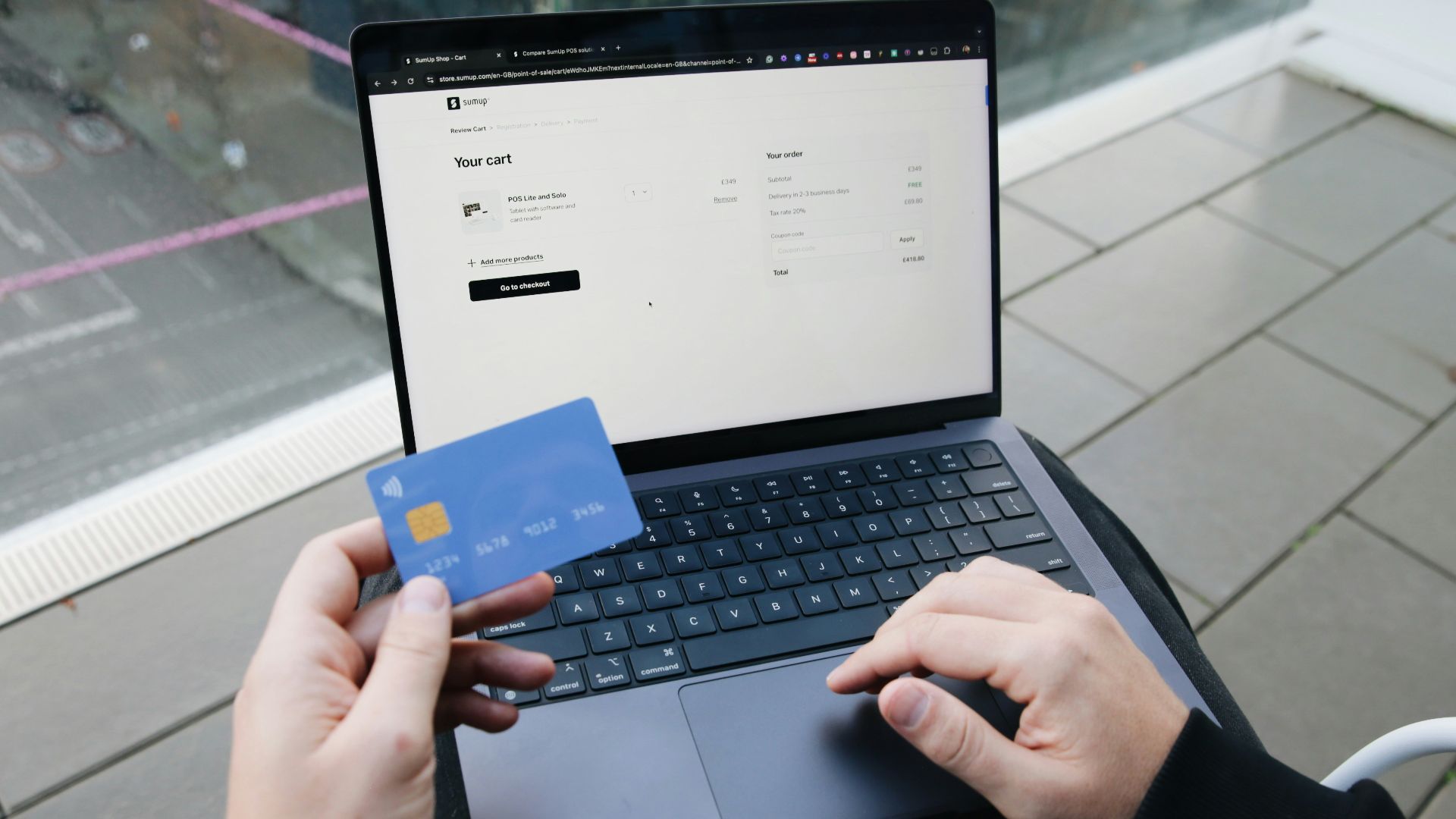 A person sitting in a chair with a laptop and a credit card