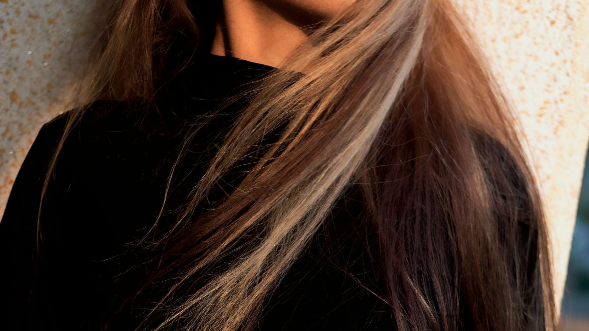 a woman with long hair standing next to a wall