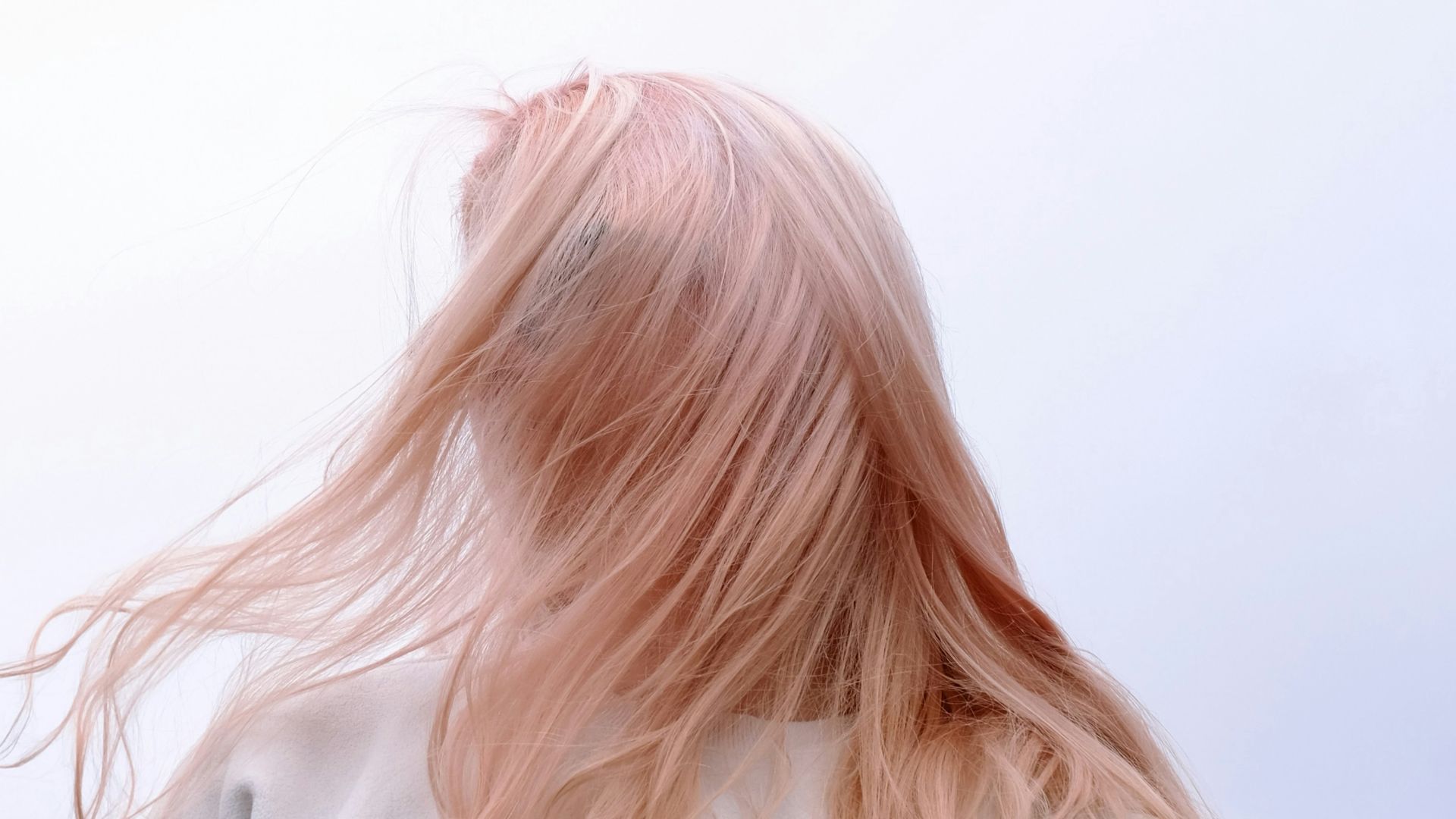 a woman with pink hair standing in front of a cloudy sky