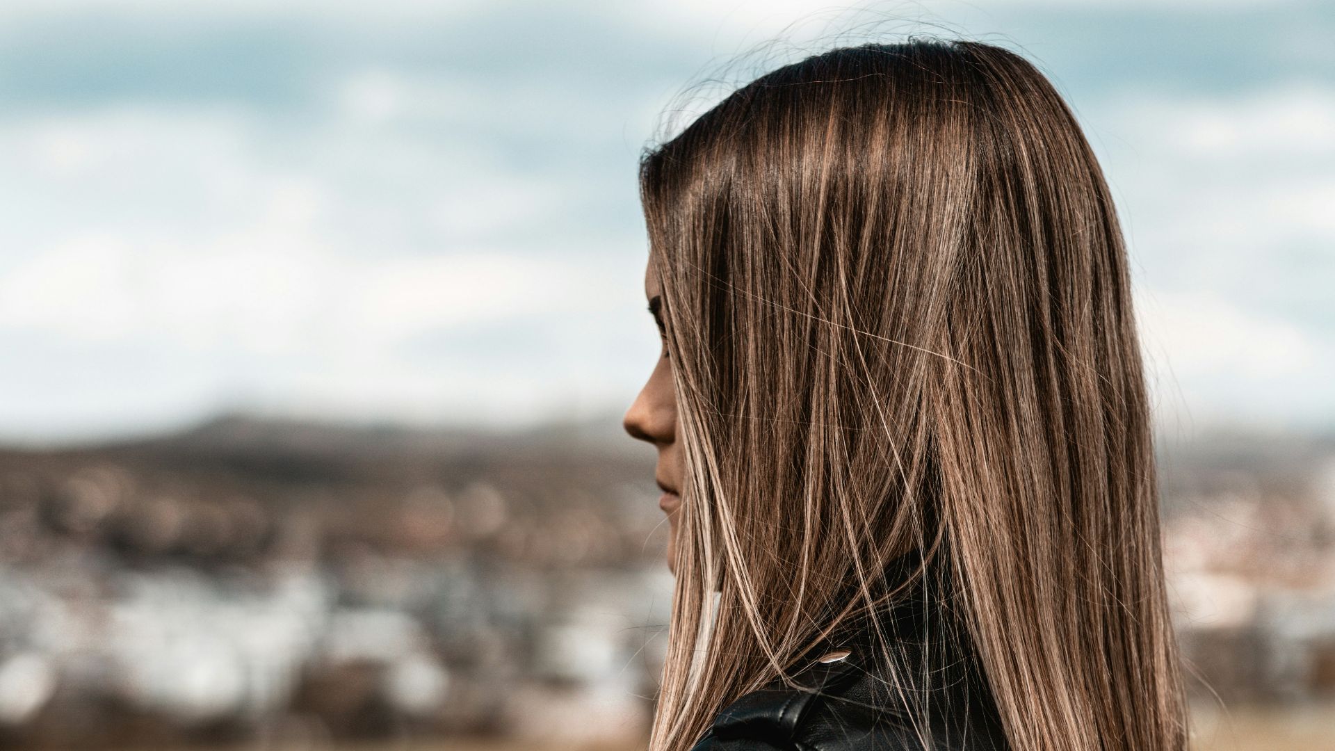 woman in black leather jacket standing on green grass field during daytime