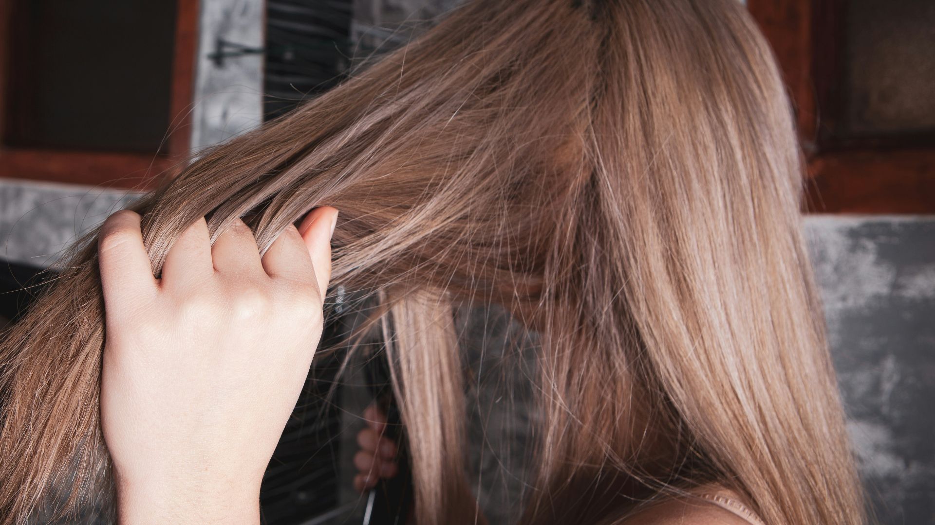 Woman drying her long blonde hair with a hairdryer