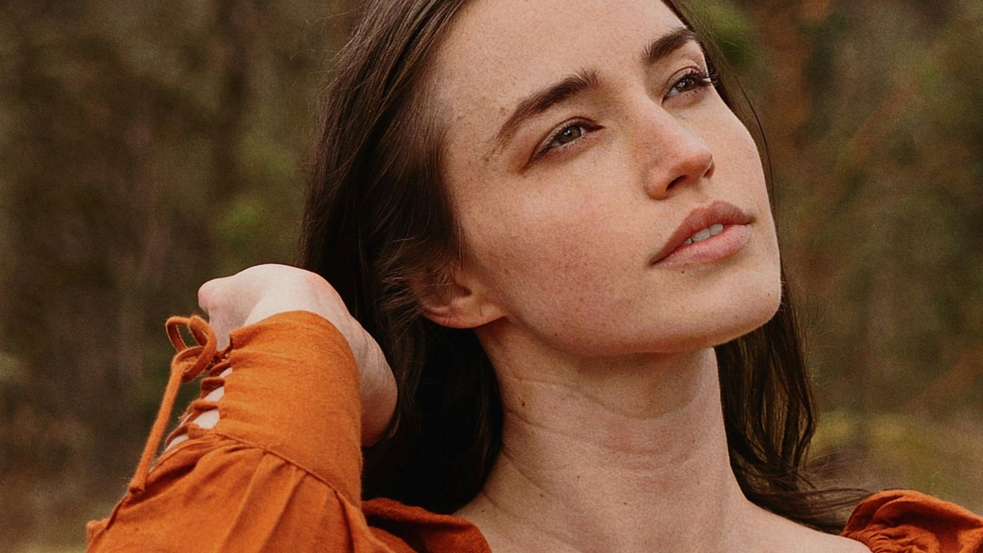 a woman in an orange dress sitting in a forest