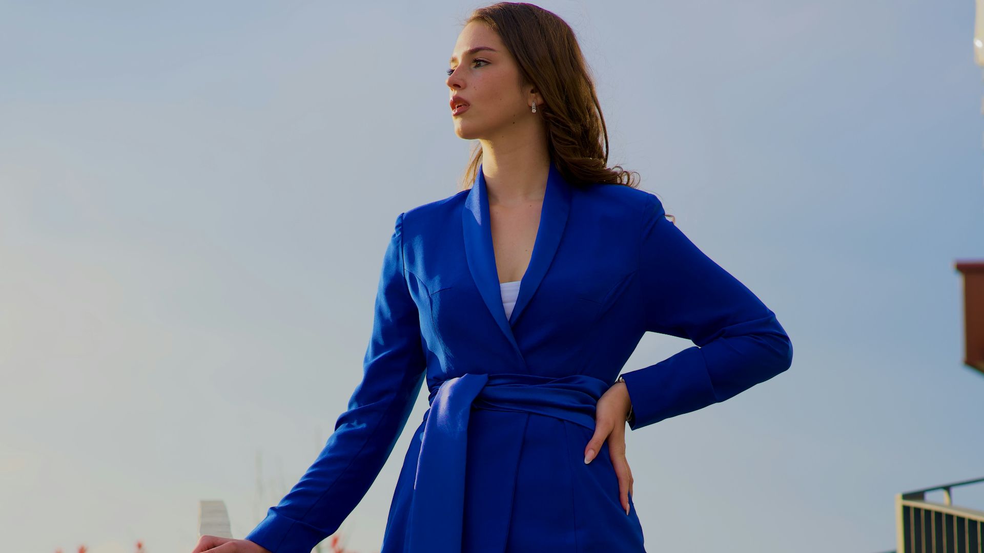 a woman in a blue suit standing on a ledge