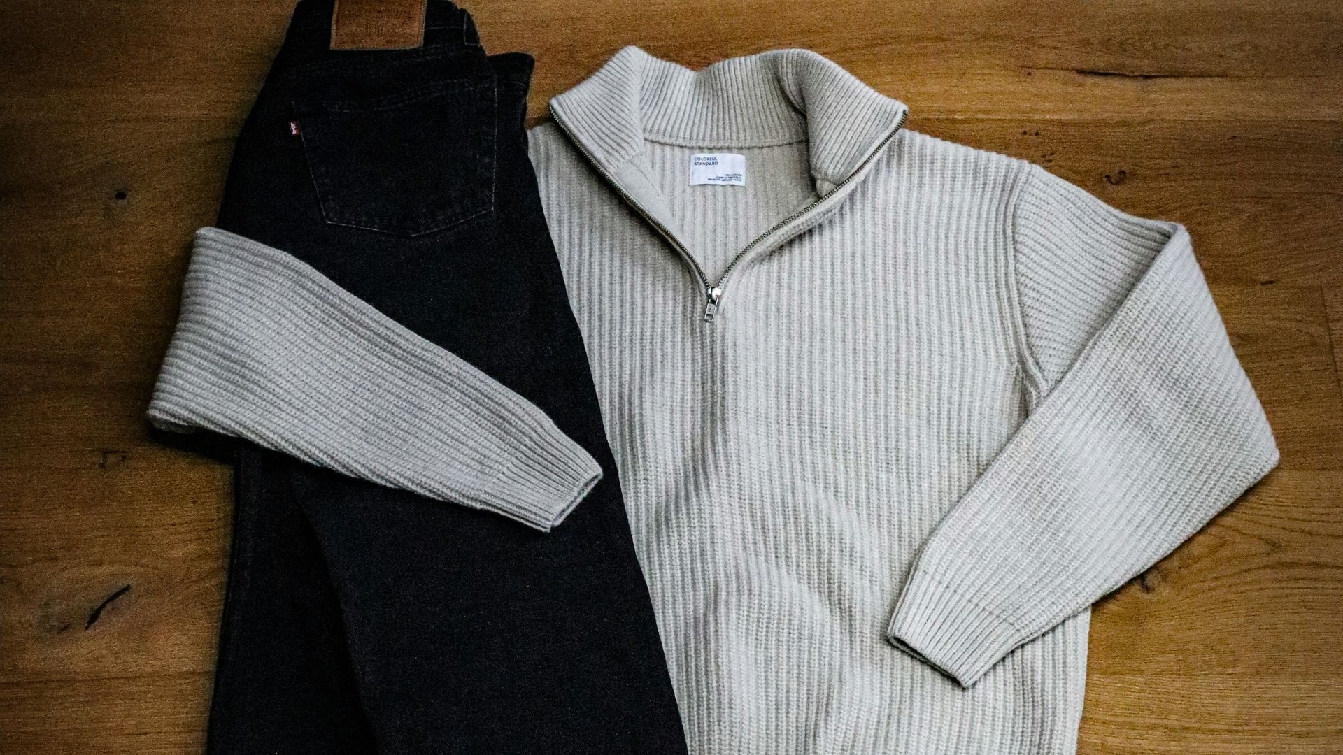 A pair of sneakers and a sweater on a wooden floor