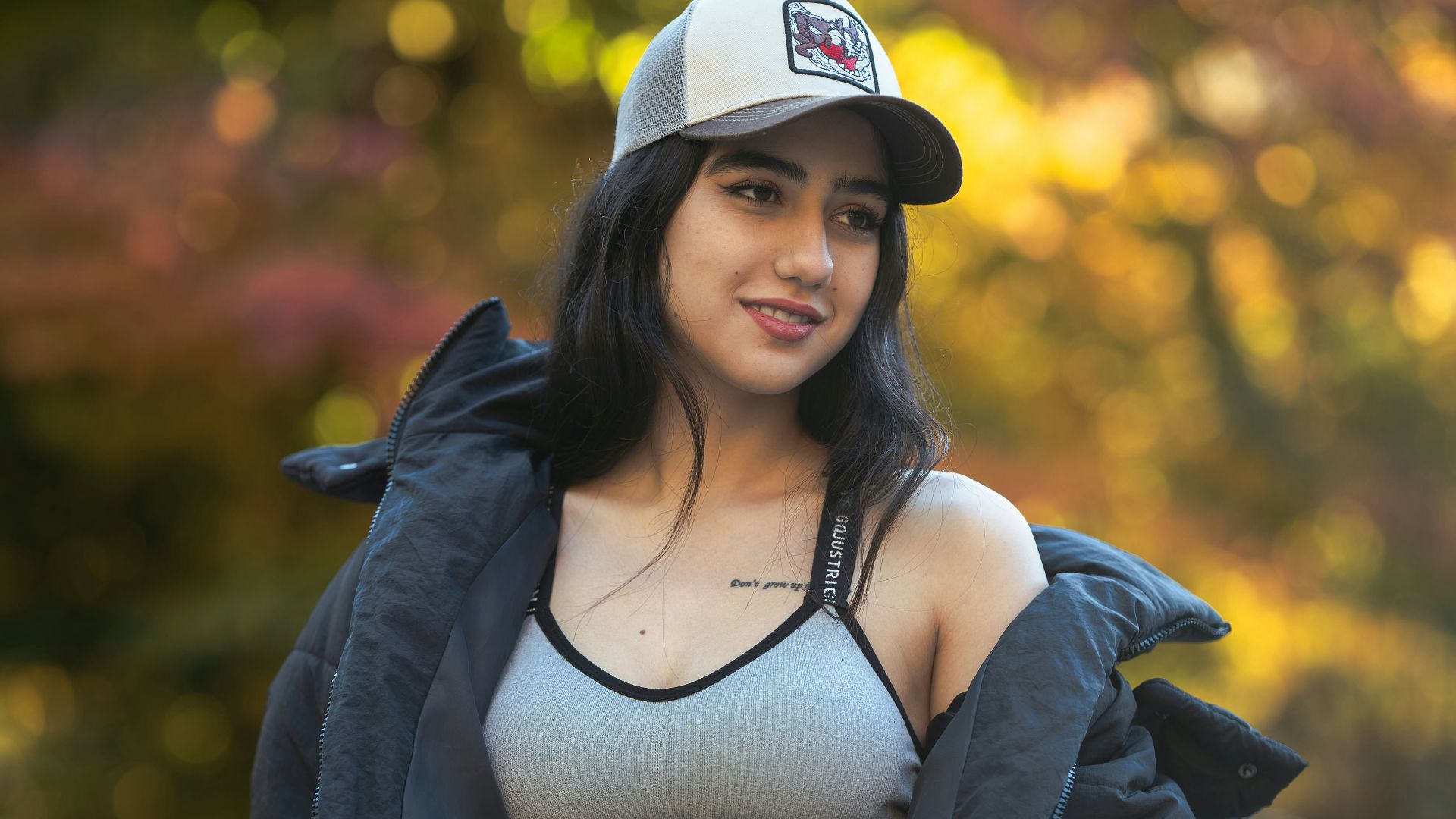 A woman poses with a jacket and cap.