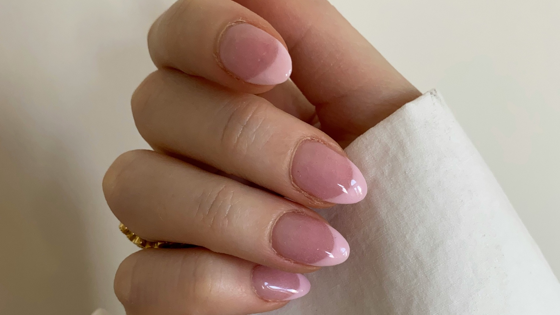 person with pink manicure on white textile
