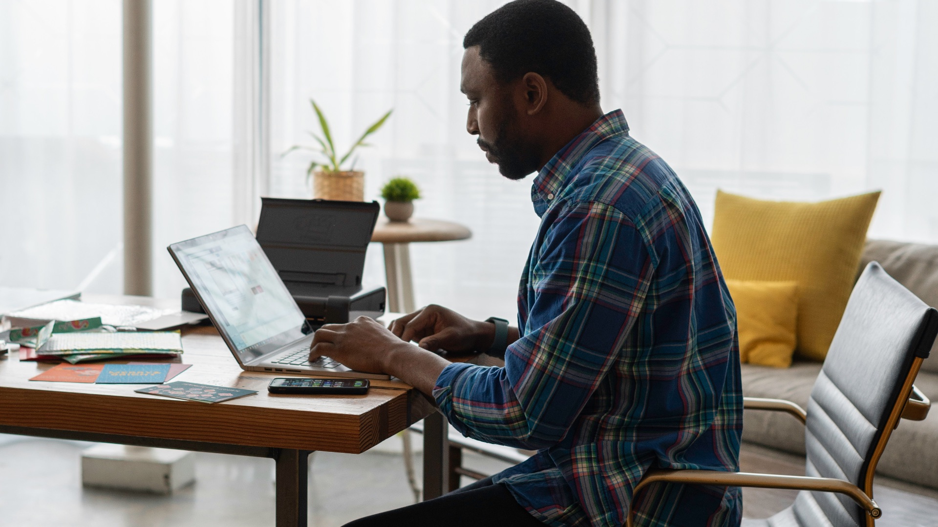 man in blue and white plaid dress shirt sitting on chair using laptop computer