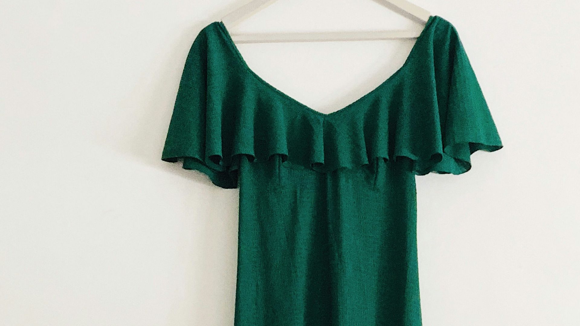 green sleeveless dress hanged on white wall