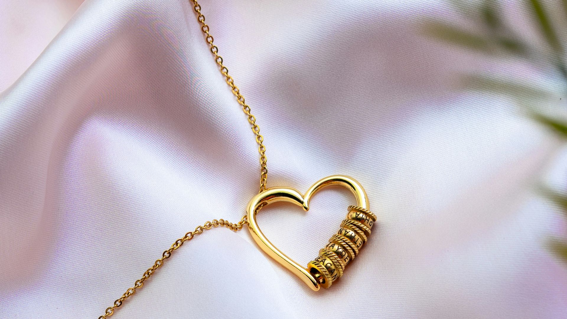 Gold heart necklace with wrapped detail on pink satin