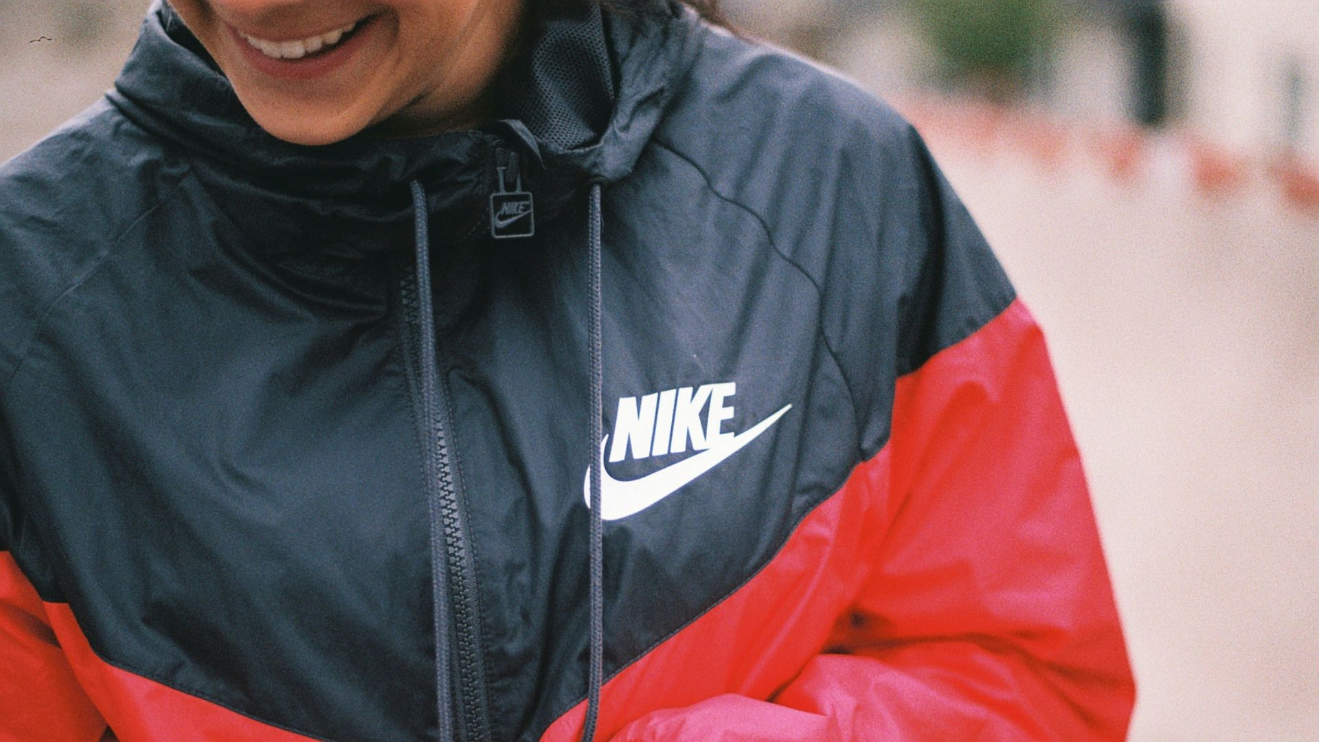 a woman in a black and red jacket smiles
