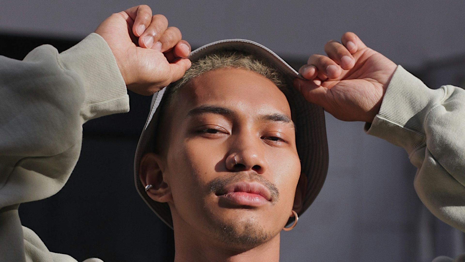 man in white sweater holding round mirror