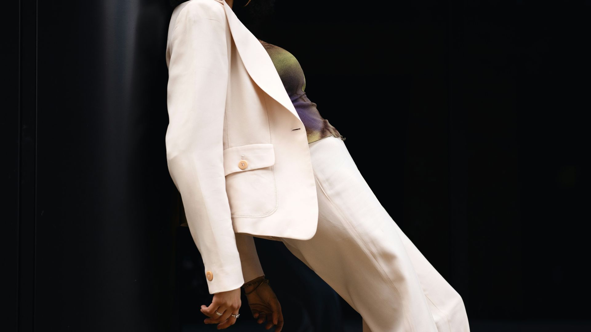 A woman poses in a white suit.