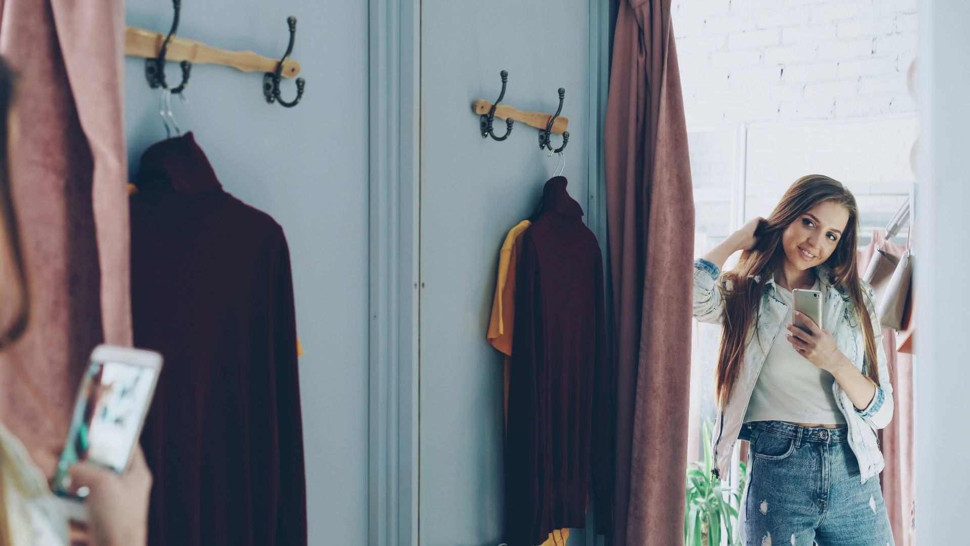 Woman takes a selfie in a clothing store's changing room.