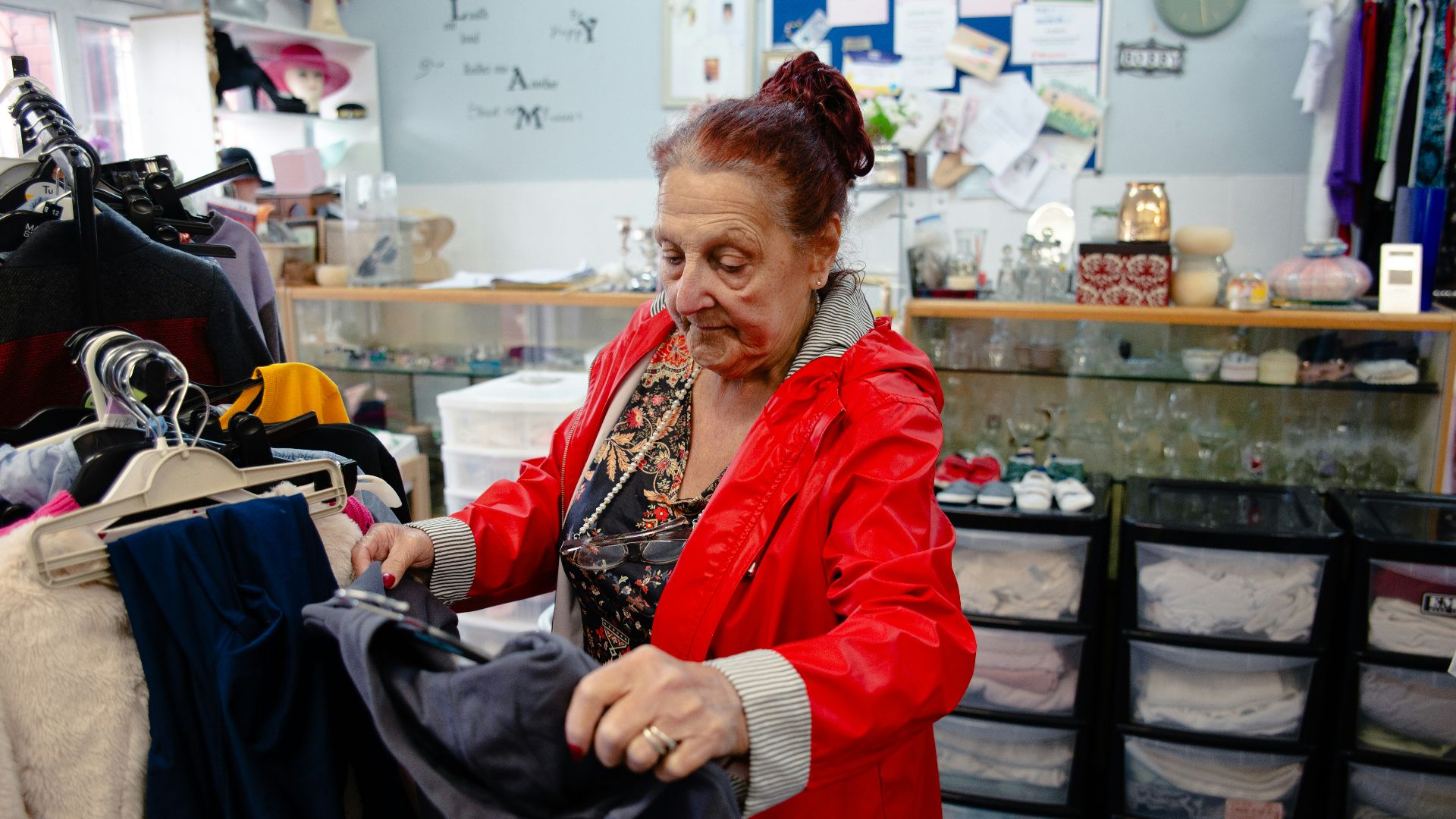 Elderly woman sorting clothes in a store.