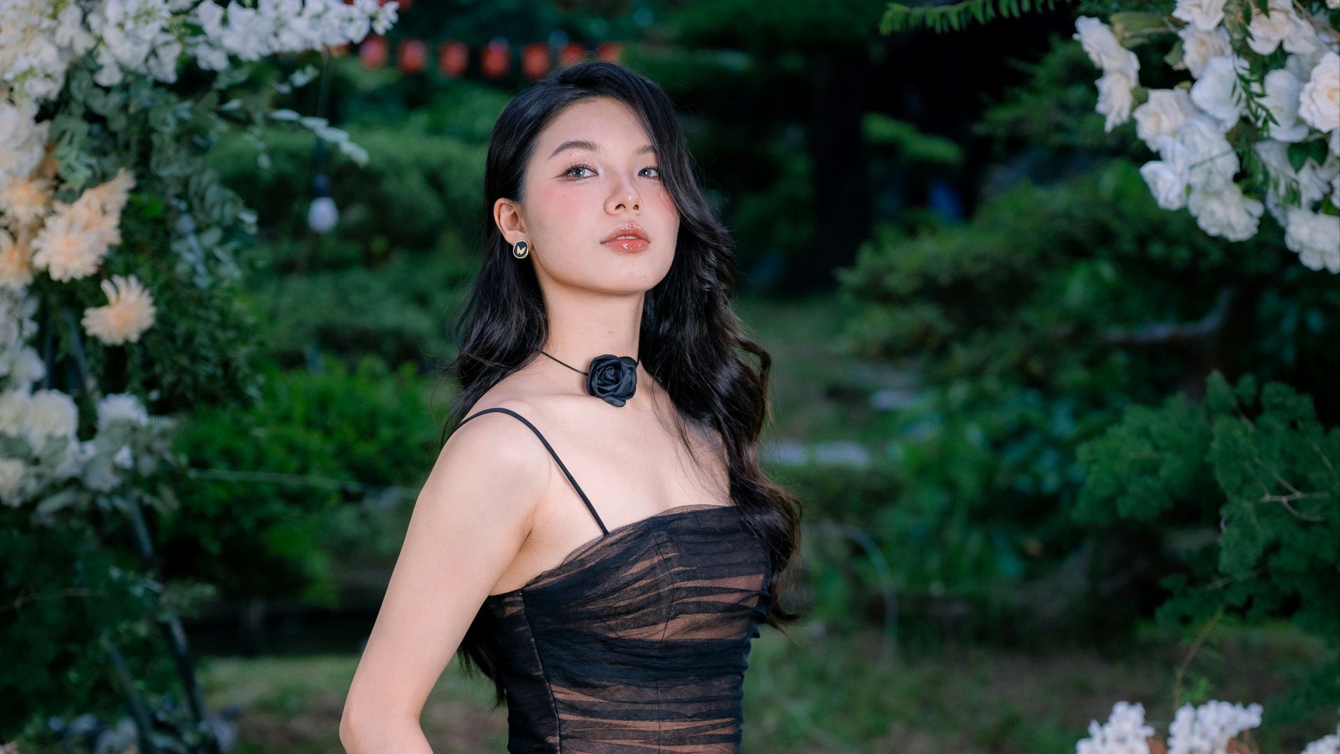 Young woman in elegant black dress in garden