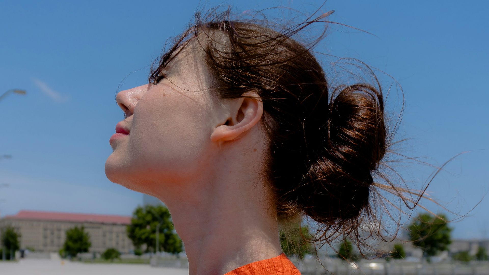 Young woman in orange top with hair bun