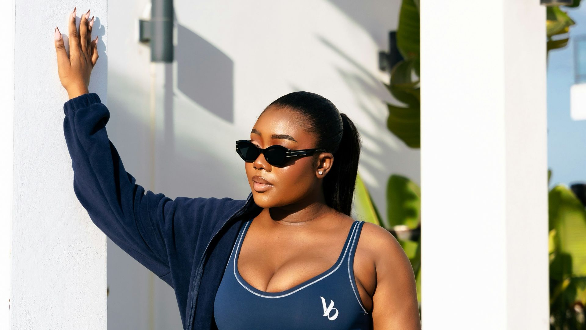 A woman in navy activewear holds a pink gym bag.