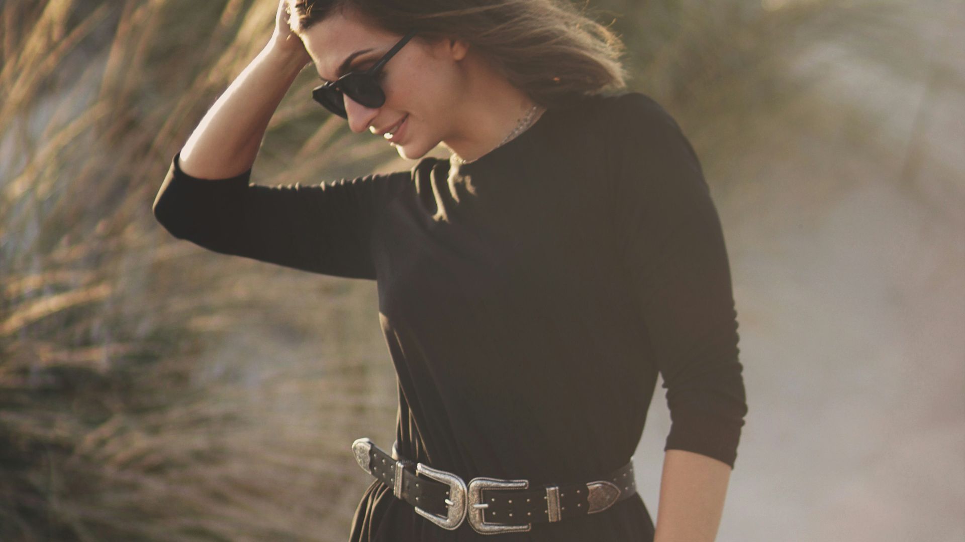 woman touching hair standing on sand