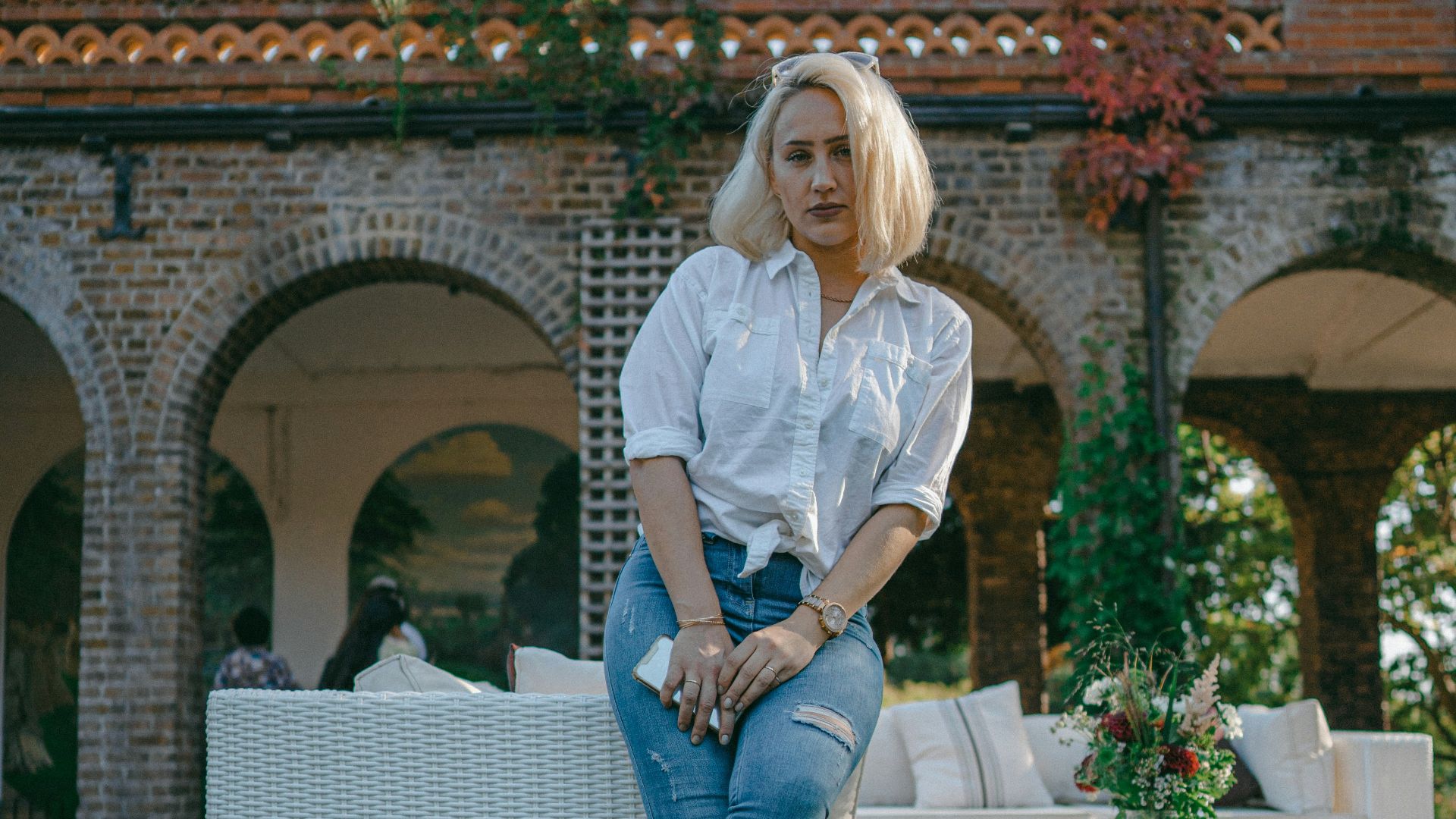 woman in white dress shirt and blue denim jeans standing on green grass field during daytime