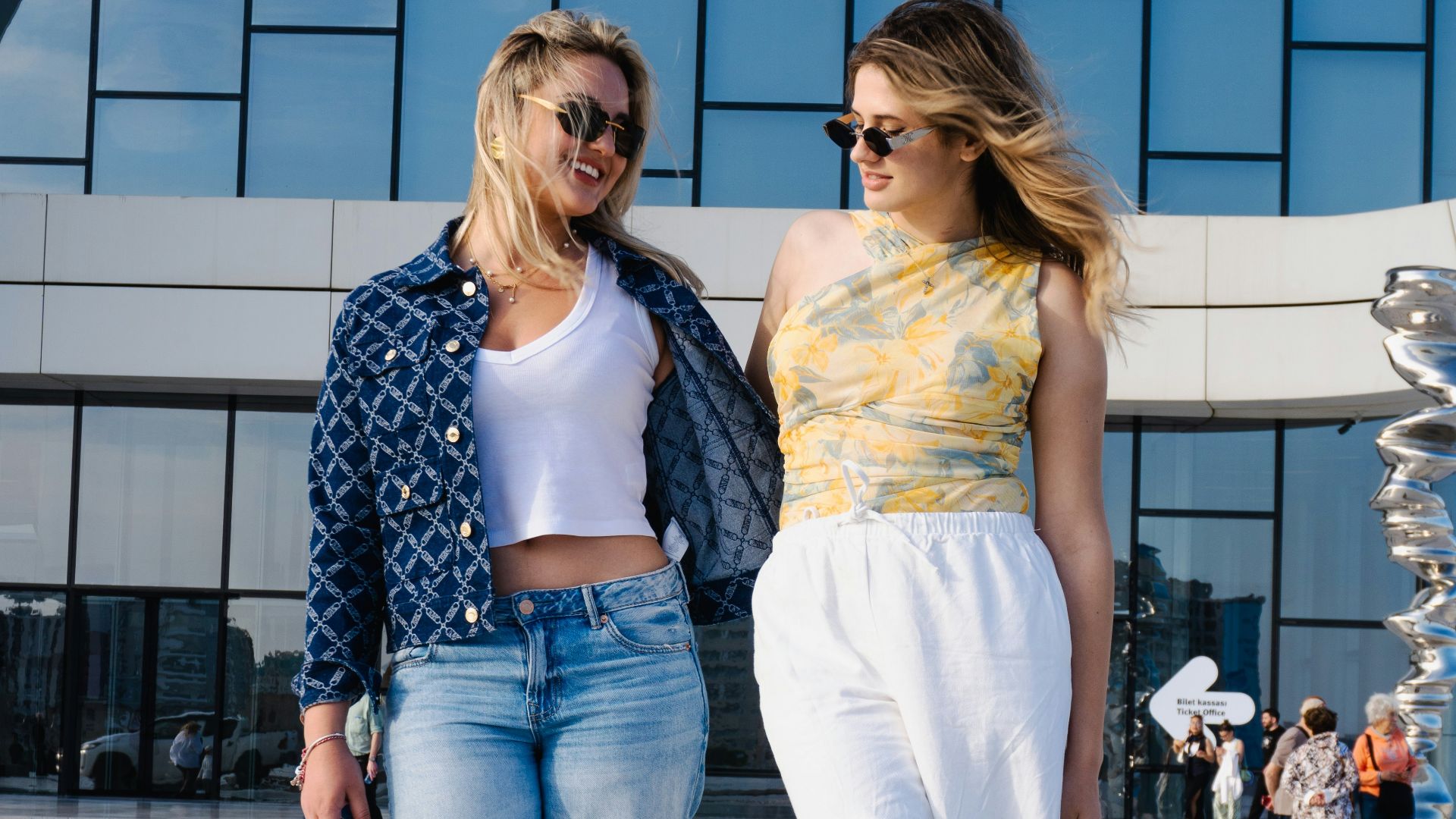 Two women walking in front of a modern building.