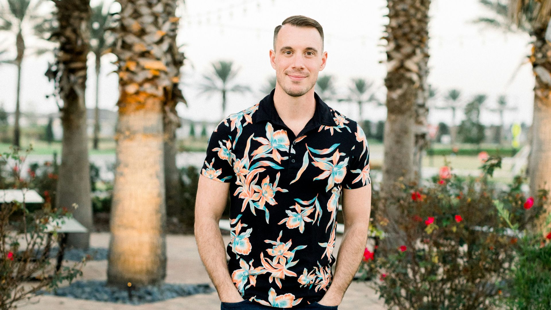 a man standing on a sidewalk in front of palm trees