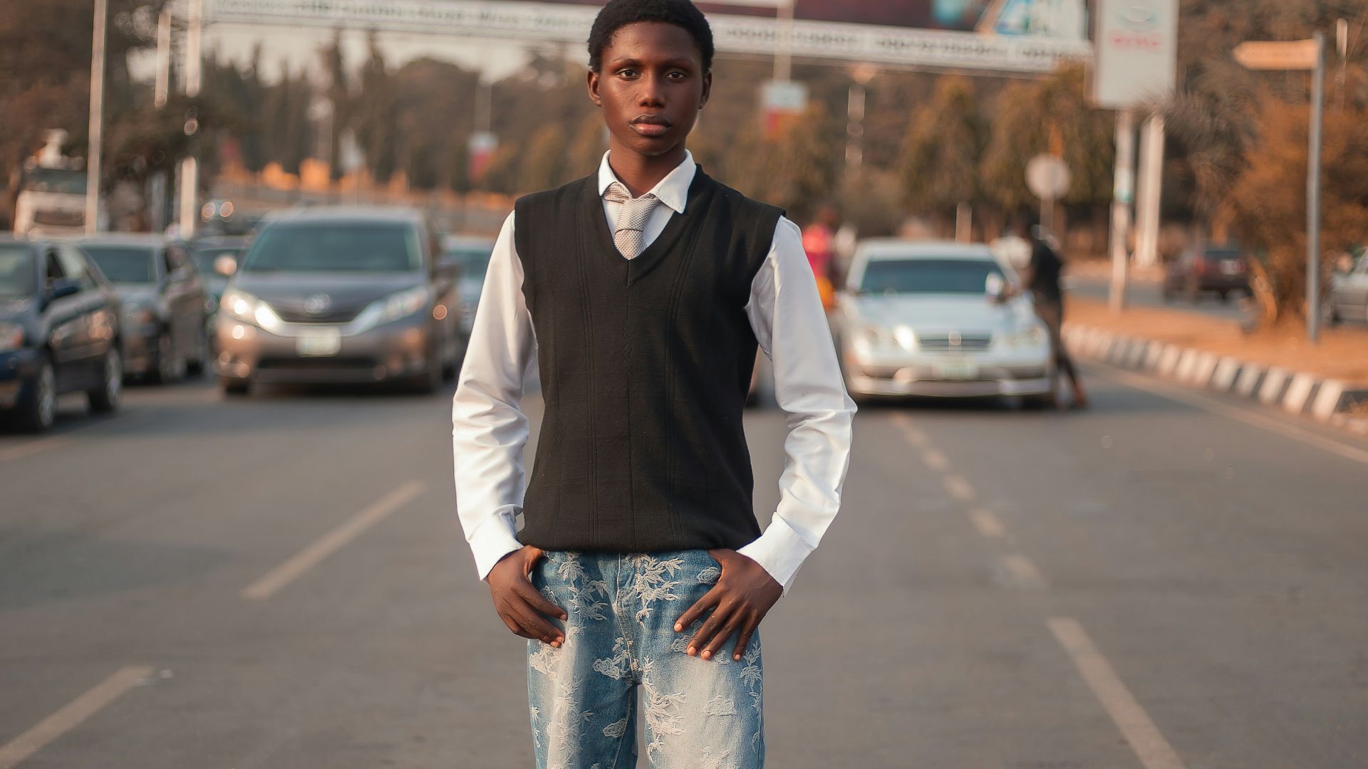 Young man stands in the middle of a road.