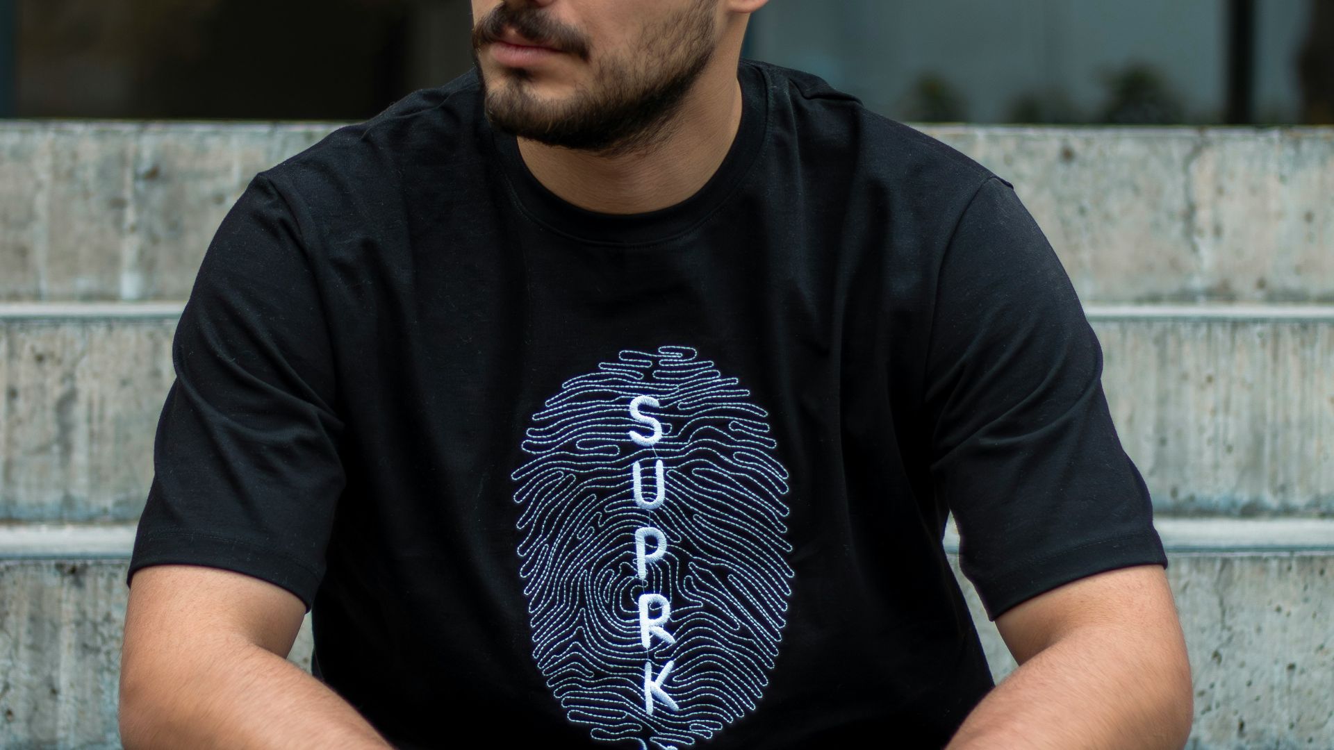 Man in t-shirt with fingerprint logo sitting on steps