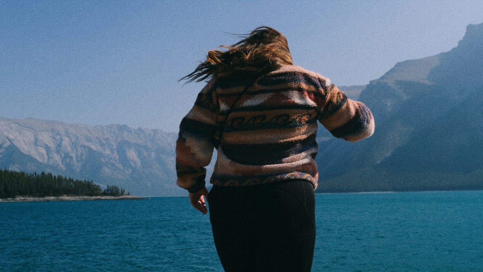 Woman standing on rocks overlooking a turquoise lake