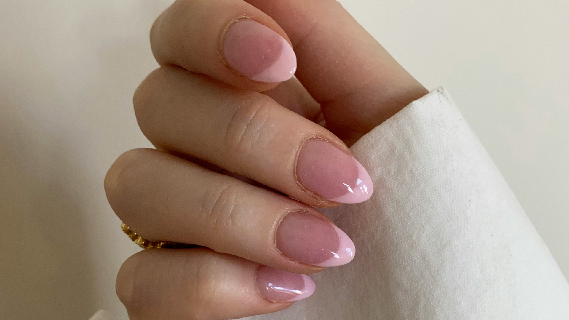 person with pink manicure on white textile