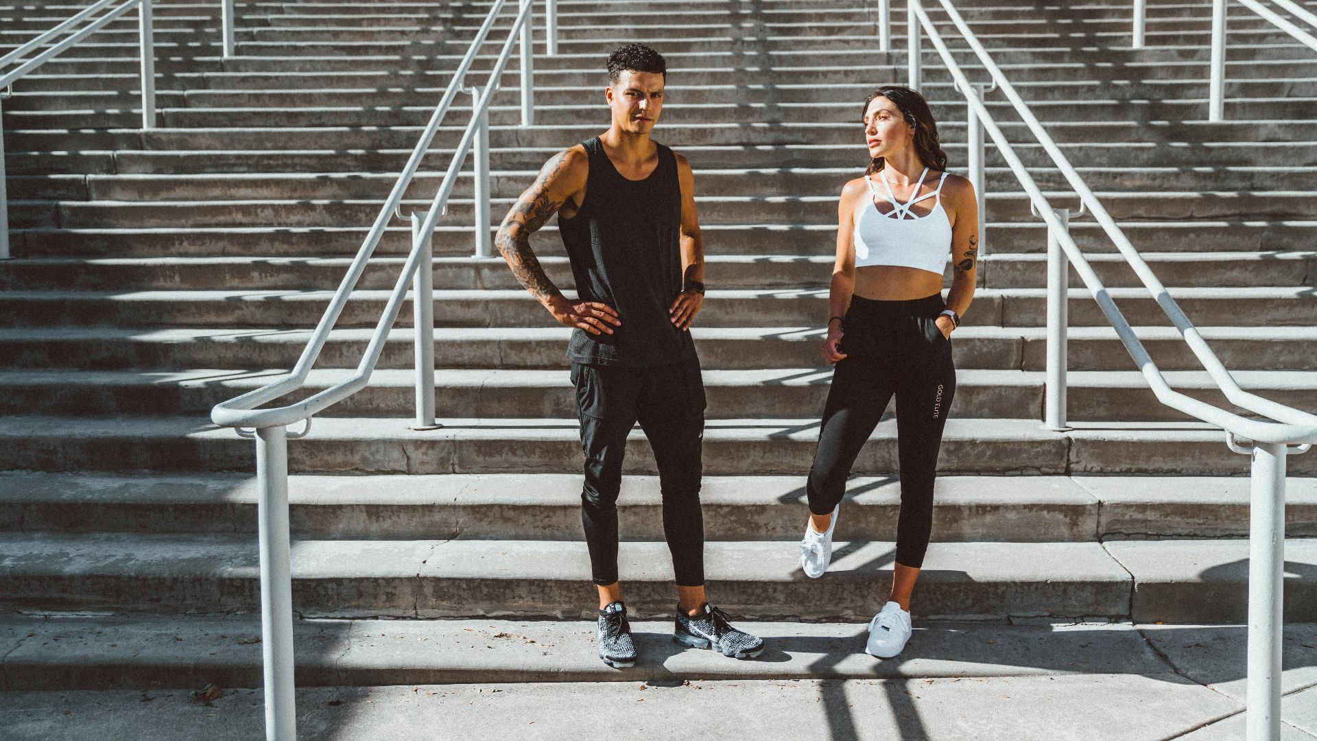 woman in black tank top and black pants standing on gray concrete stairs