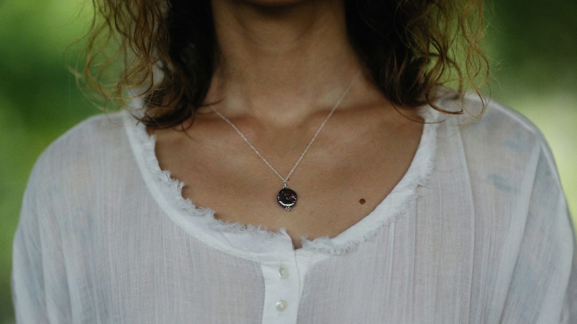 a woman wearing a white shirt and a black necklace