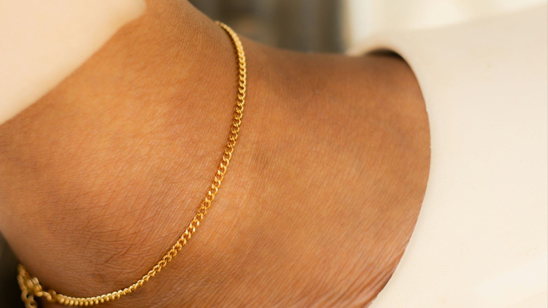 Ankle with a gold bracelet and a slipper.