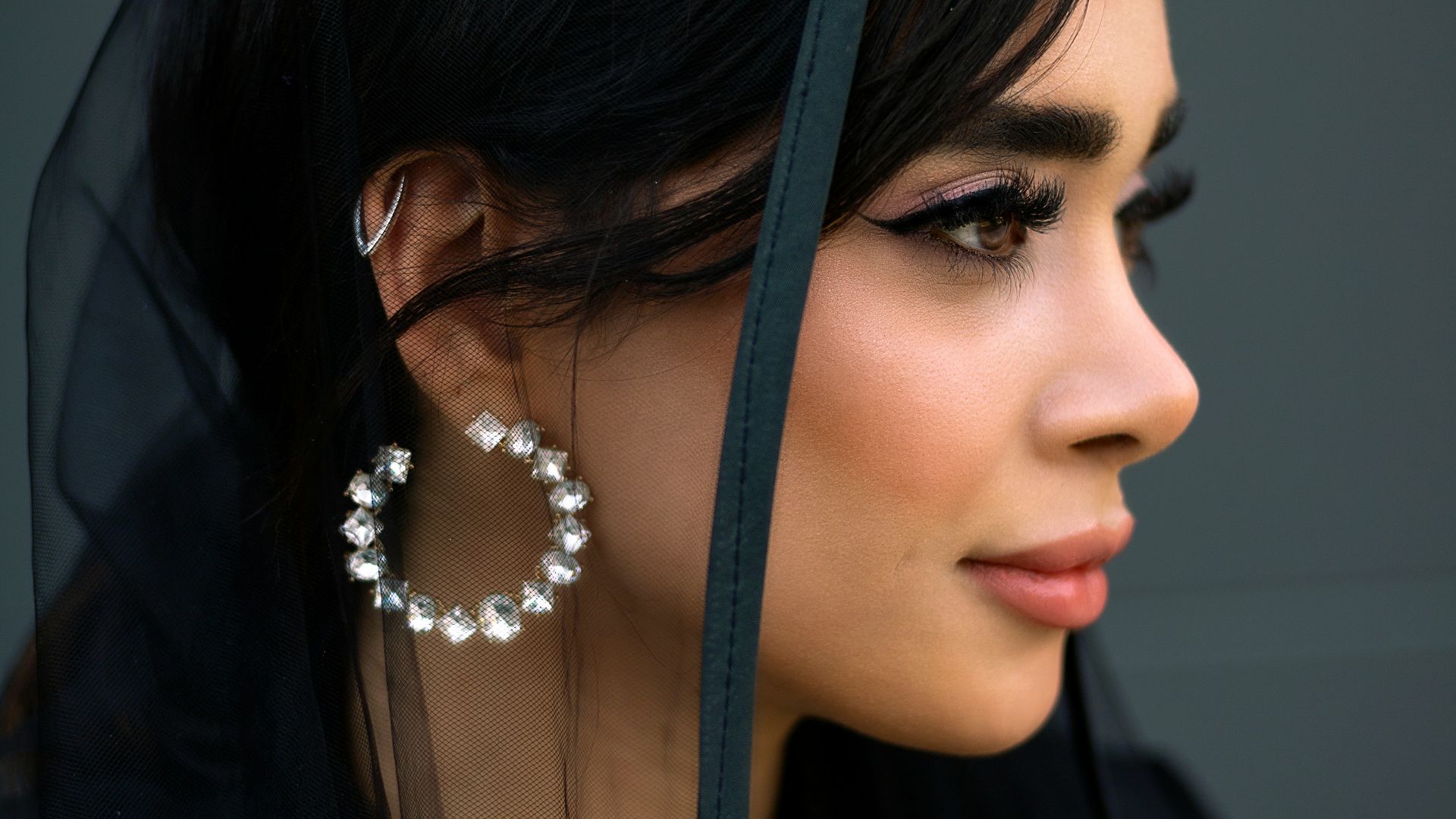 Woman wearing a black hijab and large hoop earrings.