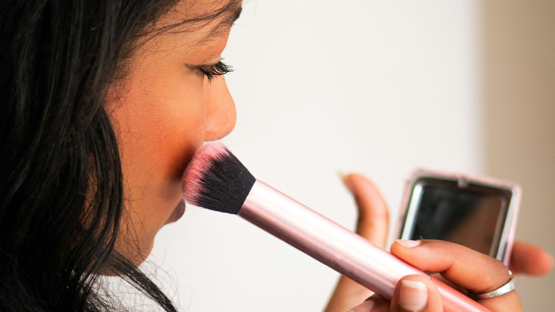 Woman applying blush with a makeup brush.