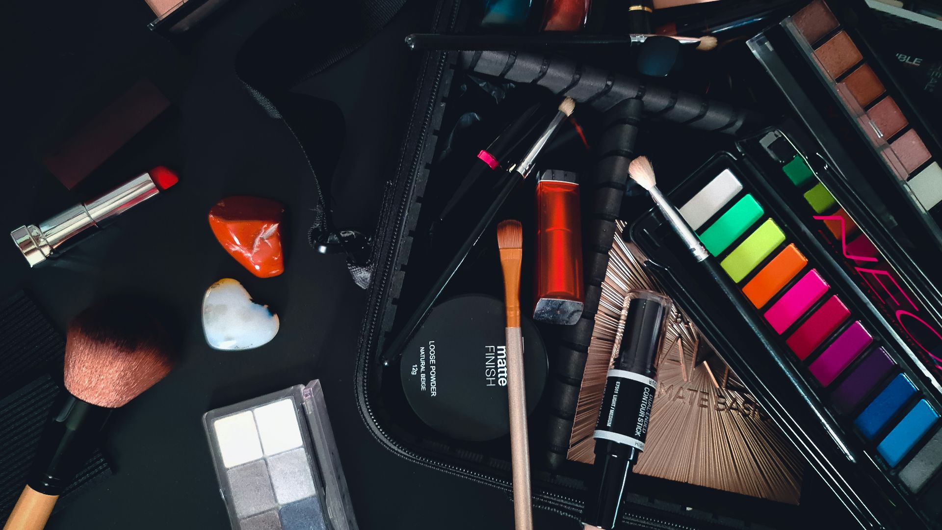 a variety of cosmetics and makeup brushes on a table
